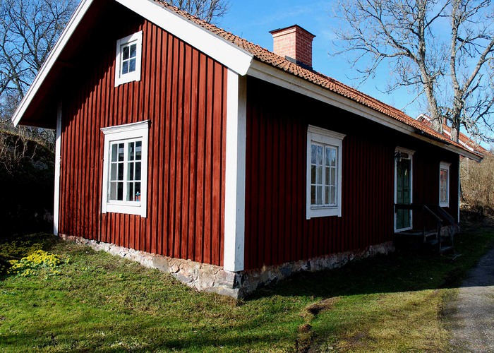 en röd byggnad med vita knutar med gräsmatta framför.